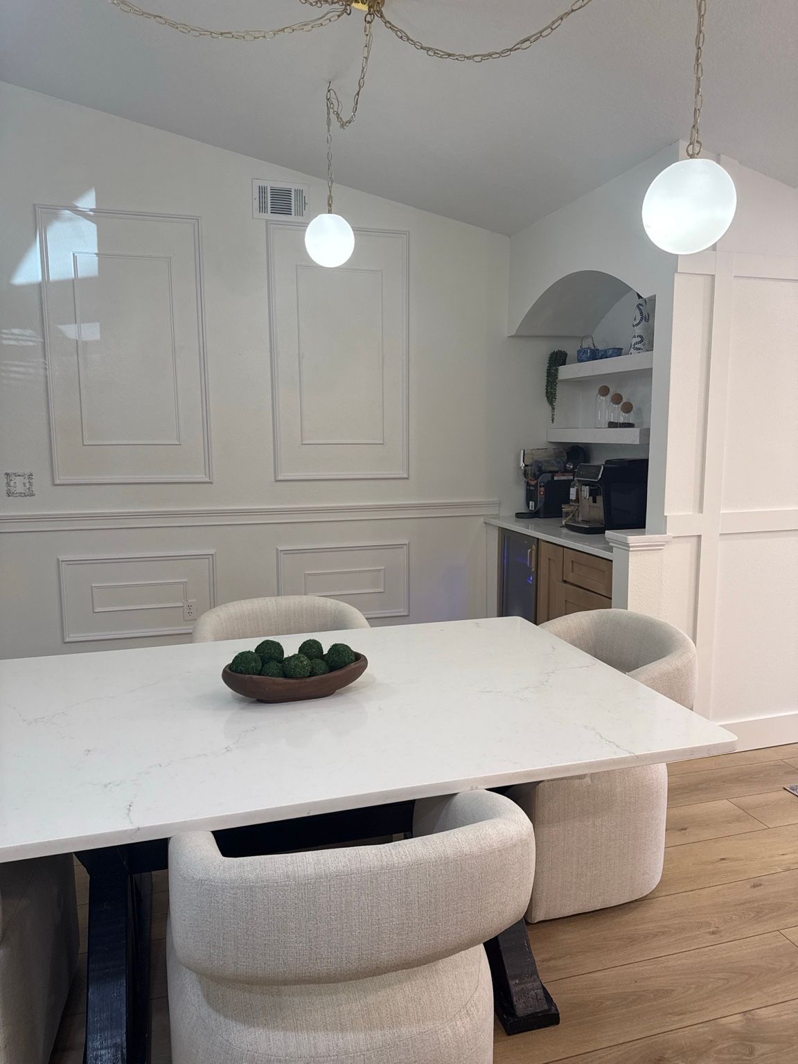Renovated dining room with picture-frame wall trim, an arched coffee bar and a paneled pantry wall